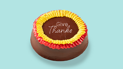 Chocolate cake decorated for Thanksgiving. Brown cake with colorful flowers on top, surrounded by a ring of red and yellow roses.